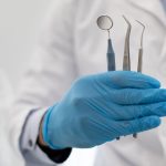 Mano de dentista con diferentes instrumentos de las especialidades odontológicas