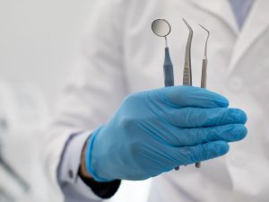 Mano de dentista con diferentes instrumentos de las especialidades odontológicas