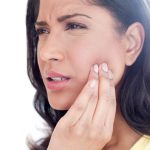 Mujer siente dolor dental intenso que puede requerir una Endodoncia Tipos y procedimientos